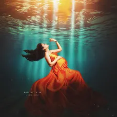 A breathtaking "underwater" portrait where the mother-to-be appears to float towards the light. The flowing orange gown creates a stunning visual against the deep blue.