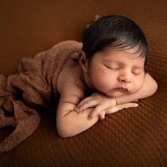This is a classic newborn pose, often called the "taco pose," where the baby is gently curled up. It showcases their tiny hands and feet while keeping them snug and secure.