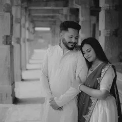 A classic black and white portrait of the couple in a pillared corridor. Using monochrome adds a timeless, artistic feel to this maternity photo, emphasizing emotion over color.