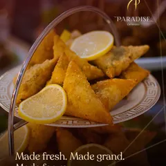 Made fresh, made grand, made for you. Our crispy samosas are a classic Indian snack, served elegantly on a tiered platter with fresh lemon wedges.