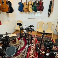Our drum room, equipped with multiple electronic kits and surrounded by guitars. This space is designed for both individual practice and energetic group rhythm sessions.
