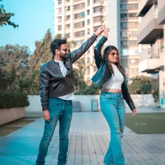 A fun and dynamic shot in a modern urban setting. The couple is dancing, full of energy and laughter, showing that a city shoot can be playful and candid.