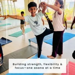 Building strength, flexibility, and focus, one asana at a time. A teacher provides gentle support to a young student in Natarajasana (Dancer's Pose) during our Bala Shivir.