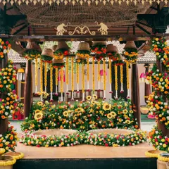 A vibrant Haldi mandap bursting with color. The setup features a mix of sunflowers, marigolds, and roses, with hanging floral baskets and garlands creating a festive and joyful backdrop for the ceremony.