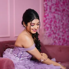 A close-up of the lavender gown's off-shoulder design and detailed corset, taken on our pink sofa for a soft, feminine feel.