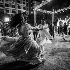 A high-energy garba dance. The motion blur and the swirl of the lehenga capture the vibrant spirit of a Gujarati sangeet night.