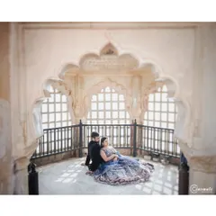 A quiet moment inside a palace, using the intricate arches and natural light from the jharokha windows to frame the couple. This shot highlights the stunning architecture while keeping the focus on their connection.