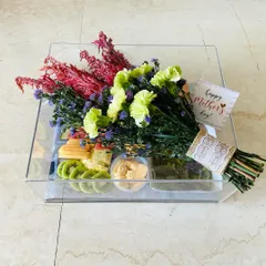 A Mother's Day pamper hamper designed for breakfast in bed. This acrylic tray holds a fresh floral bouquet alongside fruits, dip, and pastries for the perfect morning treat.