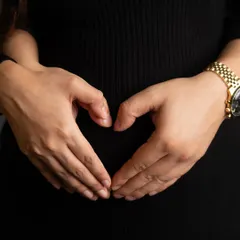 A simple, beautiful gesture. A mother's hands forming a heart over her baby bump is a universal symbol of love, protection, and the incredible bond she already shares with her child.