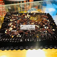 A delicious-looking square chocolate cake topped with chocolate crumble and white chocolate chips.