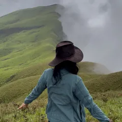 A trekker spreads her arms, embracing the stunning view of the Netravathi ridge line disappearing into the mist.
