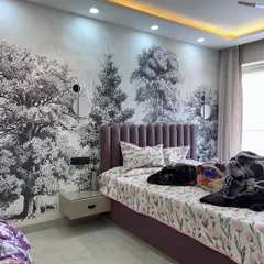 This bedroom features a beautiful full-wall wallpaper with a forest mural, creating a serene and natural ambiance. The purple channel-tufted headboard adds a pop of color.