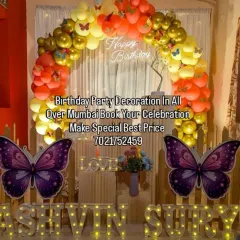 A beautiful butterfly-themed setup perfect for a home celebration. It includes a warm-toned balloon arch, large decorative butterflies, and light-up marquee letters spelling out the names.