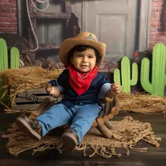 Howdy, partner! This handsome little Texan is ready for an adventure in our cowboy-themed setup, complete with a hat, bandana, and rustic props.