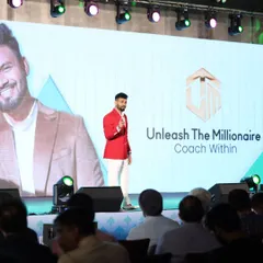 Mr. Purushottam Hambarde commanding the stage in a vibrant red double-breasted blazer and white trousers. We designed this standout look for his special "Unleash The Millionaire" event.