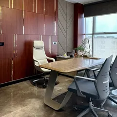 A side profile of the executive office, highlighting the unique Z-shaped leg design of the desk and the high-back leather chair. The design focuses on modern forms and high-quality materials.