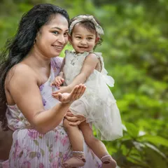 A mother and her toddler share a sweet, smiling moment. The natural, soft light highlights their happy expressions and the genuine connection between them.