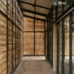 An interior corridor at the Artist Residency, where the bamboo screen facade filters sunlight into the space. This transitional area is neither fully inside nor out, creating a sheltered walkway that remains connected to the natural environment.