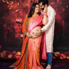 We love capturing the beauty of tradition. This couple's maternity portrait, set against a rich, warm backdrop with hanging lamps, highlights their connection and the elegance of a traditional saree, complete with intricate jewelry and henna.
