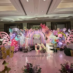 The main stage is a breathtaking display of pastel arches, balloon clouds, and oversized butterfly cutouts, with a large light-up "ONE" to celebrate the milestone.