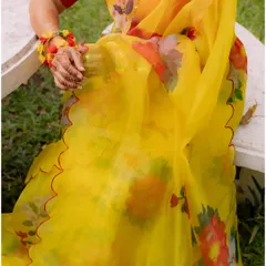 A detail shot of the bride's beautiful yellow floral saree and her henna-adorned hand. A perfect capture of the vibrant colors and details of a Haldi ceremony.