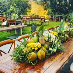 A long wooden table adorned with a runner of fresh coconuts, bananas, pineapples, and local foliage. This zero-waste setup proves that sustainable decor can be incredibly lush and opulent.