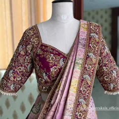 A magnificent bridal lehenga or saree set in magenta and pink. The blouse is covered in heavy zardosi work, and the saree or dupatta has a matching embroidered border.