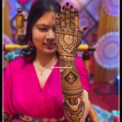 A bride showing the detailed mehendi on the back of her hand. The design includes personal initials and symbolic figures, perfectly complementing her wedding look.