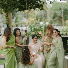 The bride, seated on a swing, is surrounded by her smiling bridesmaids. This candid and interactive group photo is full of life and captures the strong bond of their friendship.