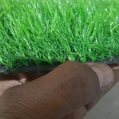A close up showing the thickness and texture of a 25mm artificial grass sample. You can see the individual blades and the sturdy backing that holds them in place.