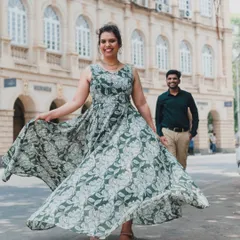 A playful, candid shot with the bride-to-be in the foreground and her partner in the background, set against the elegant facade of a heritage building in Mumbai.