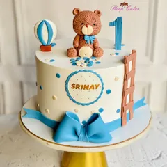 A sweet teddy bear themed cake for Srinay's first birthday. This fondant cake features a cute bear, a hot air balloon, and a big blue bow, creating a classic and adorable look.