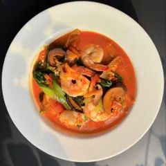 A Naga-style Prawn and Mushroom dish. The prawns and mushrooms are cooked in a light, oil-free broth with bamboo shoot extract and herbs, creating a simple yet deeply flavorful curry.