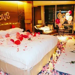A complete romantic room transformation for a special anniversary. I used a trail of rose petals and flameless candles leading to the bed, which is decorated with heart-shaped balloons and a 'LOVE' foil banner for a truly memorable surprise.