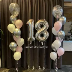 A balloon bouquet for an 18th birthday. This includes large silver foil number balloons, confetti balloons, and a mix of pink, white, and silver latex balloons.