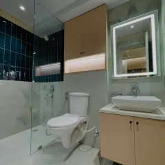 This bathroom features a modern vanity, a backlit mirror, and a glass-partitioned shower area with stylish dark green tiles. It's a perfect blend of functionality and design.