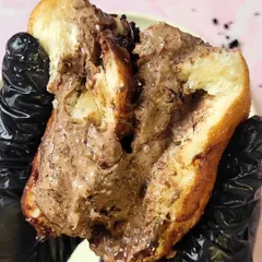 A closer look at the indulgent filling of the Bad Boy Bombolini. You can see the rich chocolate cake crumbs mixed right into the creamy custard, creating a unique and unforgettable texture.