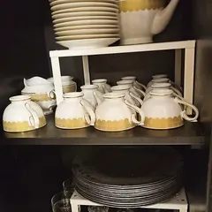 This vintage tea set is now safely organized using a shelf riser. Stacking the plates on top and arranging the cups below prevents chipping and makes the set a beautiful display piece.