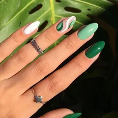 Inspired by nature, this design features shades of green in a trendy swirl pattern, paired with solid white and dark green accent nails for a fresh, modern look.