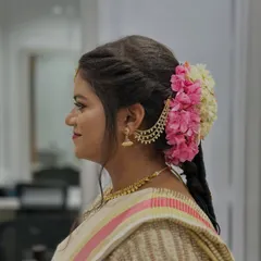 A side profile of the bridal look, showcasing the intricate hairstyle with fresh flowers that perfectly complements the makeup and attire.