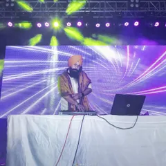 At my console with a large LED backdrop. I work with event planners to ensure my setup integrates perfectly with the stage design for a professional look.