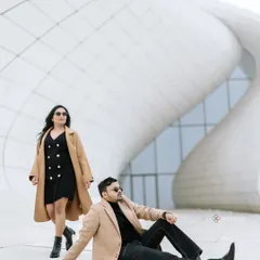 A high-fashion, editorial-style shot in front of the Heydar Aliyev Center in Baku. The minimalist white architecture and the couple's chic, coordinated outfits create a sophisticated and modern look.