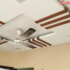 This design combines a clean white gypsum board with decorative wooden-finish beams. This approach adds warmth and a touch of classic elegance to the modern structure, perfectly integrating the ceiling fan into the central recessed area.