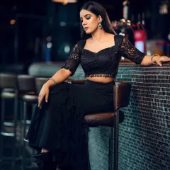 A full-length shot of the black ruffled skirt and lace crop top, showing the complete silhouette in a chic, dimly lit bar setting.