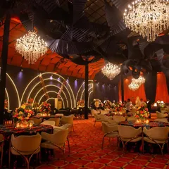 A grand view of our Diwali poker gala, a perfect inspiration for a luxurious cocktail night. The space is dominated by magnificent crystal chandeliers, a dramatic ceiling, and a rich color palette of orange and black.