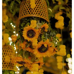 A close-up of the beautiful Haldi decor, with sunflowers and marigolds cascading from woven baskets, illuminated by fairy lights.