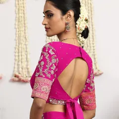 The back of this fuchsia blouse reveals a modern keyhole design with a delicate tie-up, blending contemporary style with traditional elegance. Every angle is designed to be a statement.