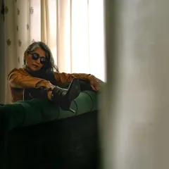 A moody, rock and roll inspired shot. Lounging on a green velvet couch, this image captures a cool, rebellious spirit perfect for edgy fashion brands.
