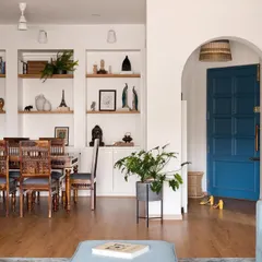 By removing an old cabinet and opening up a wall, we created this beautiful arched view into the dining room, complete with custom shelving. The bold blue door adds a pop of personality and draws the eye through the space.