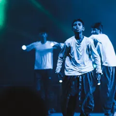 A young dancer looks up, caught in a cool blue light during a contemporary performance. My f/1.4 lens allows me to capture crisp details and mood even in the darkest stage environments.